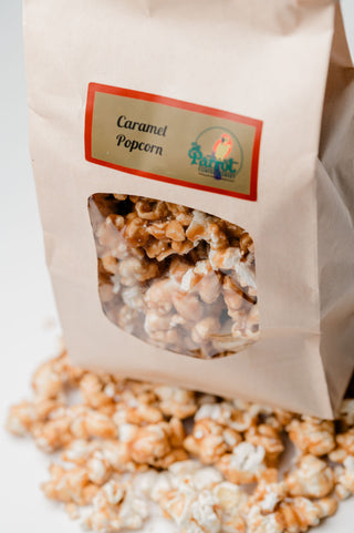 Bag of caramel popcorn with a clear window showing the popcorn inside, on a white background.