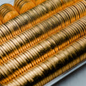 Stack of gold chocolate coins in a clear container on a light gray background