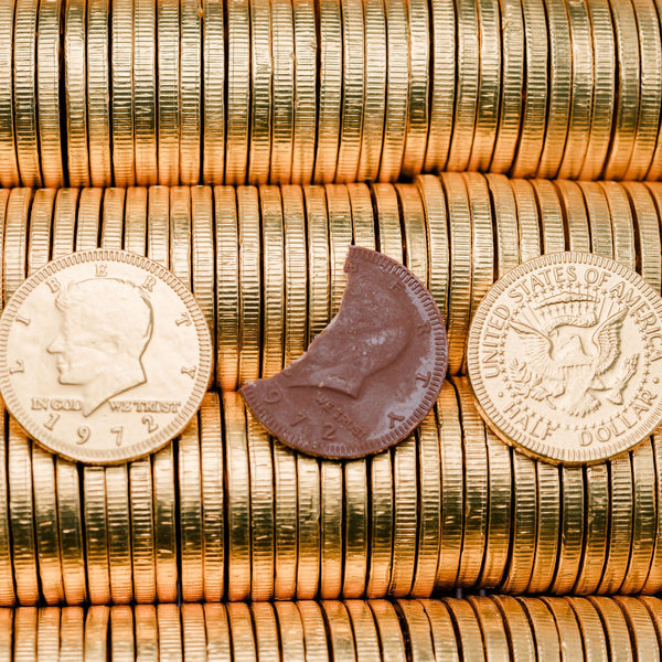 Stack of gold chocolate coins with two coins and a chocolate bar in the center.