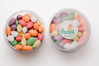Container of colorful candy with 'The Parrot' logo on a white background