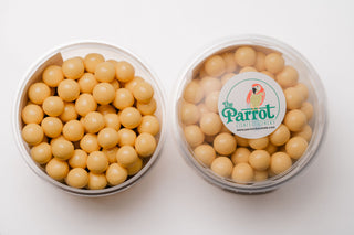 Clear container filled with round beige candy, branded 'The Parrot Company' on a white background