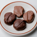 Chocolate-covered treats on a white plate with a brown rim against a light gray background