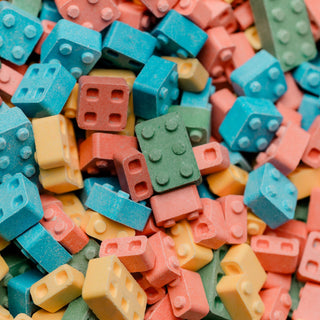 Two bags of colorful lego-shaped candies on a white background