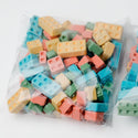 Two bags of colorful lego-shaped candies on a white background