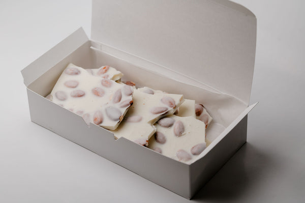 Box of white chocolate with candy eyes on a light gray background